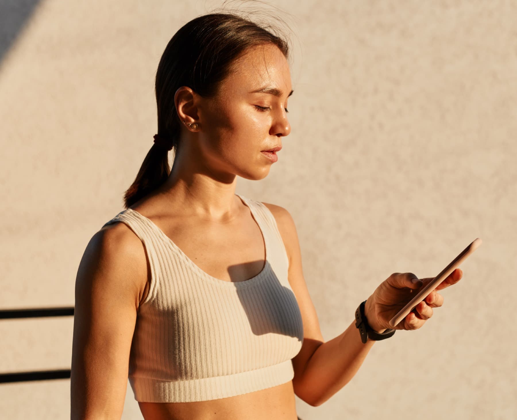 A woman looking at her phone in warm sunlight