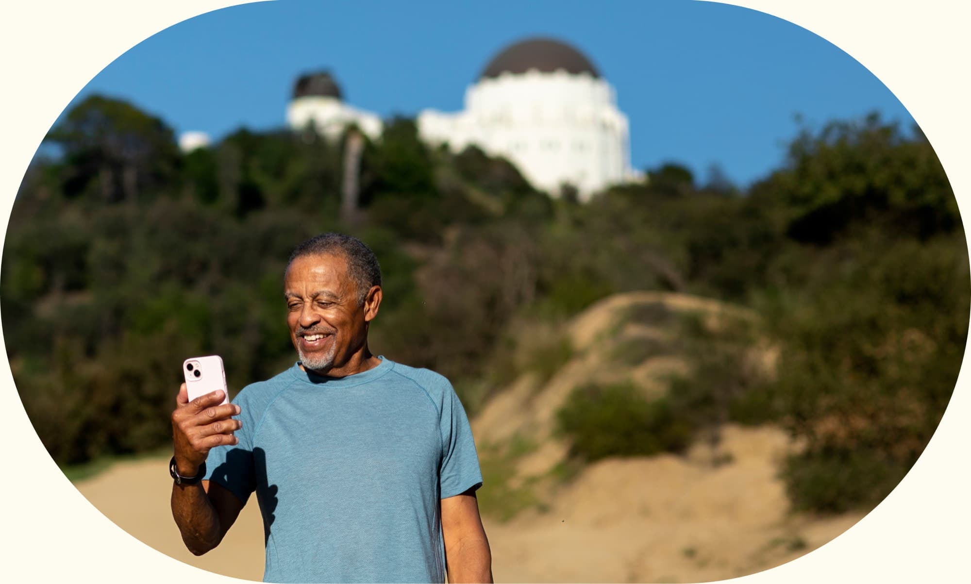 A man holding his phone and an ice cream outdoors